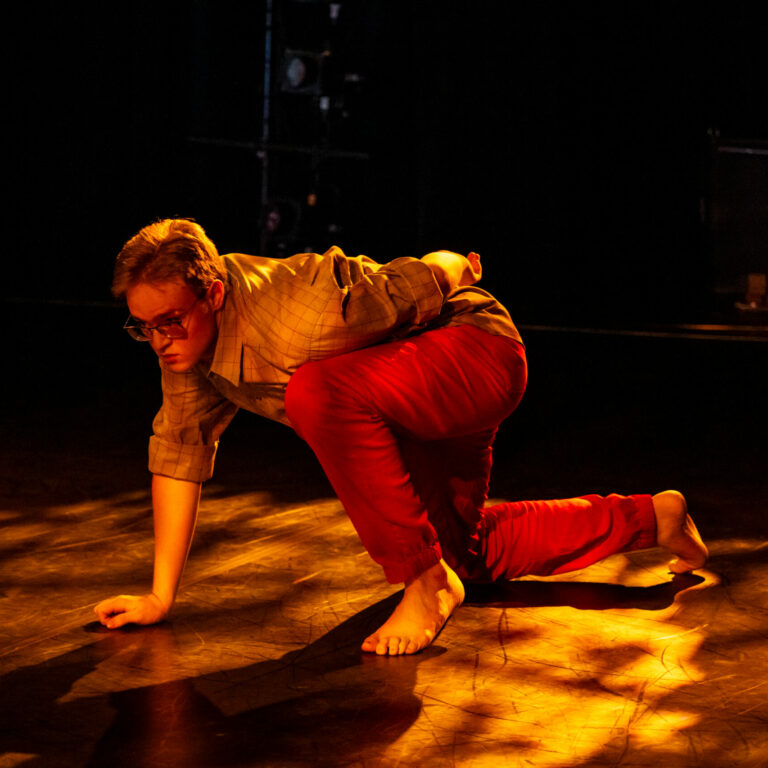 Dancer Roo Case lunging in mottled light.