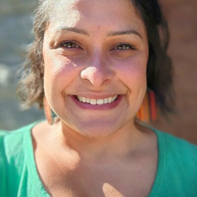 Biracial woman, Liz Perez, wearing a teal green shirt and smiling.