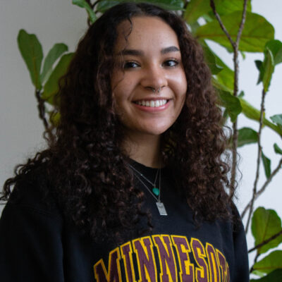 Woman, Izabella Andor, wearing a Minnesota shirt and smiling.