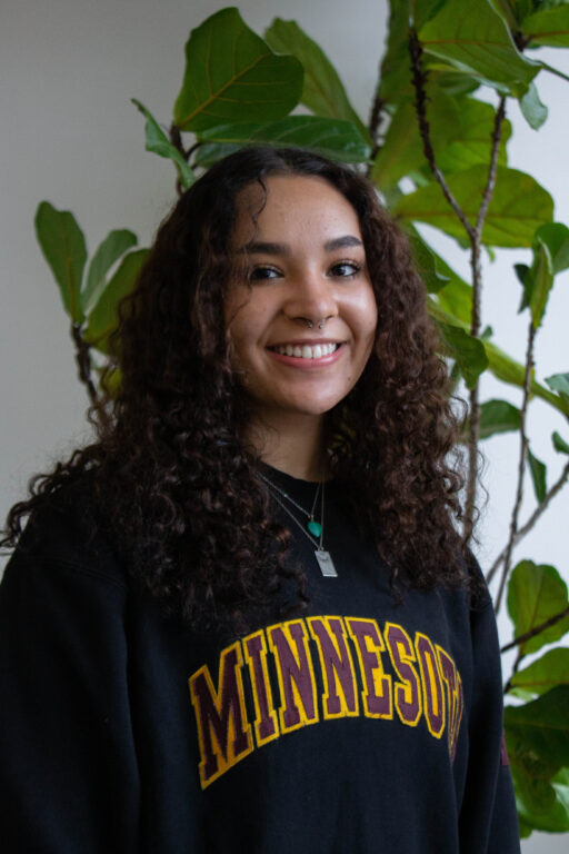 Woman, Izabella Andor, wearing a Minnesota shirt and smiling.